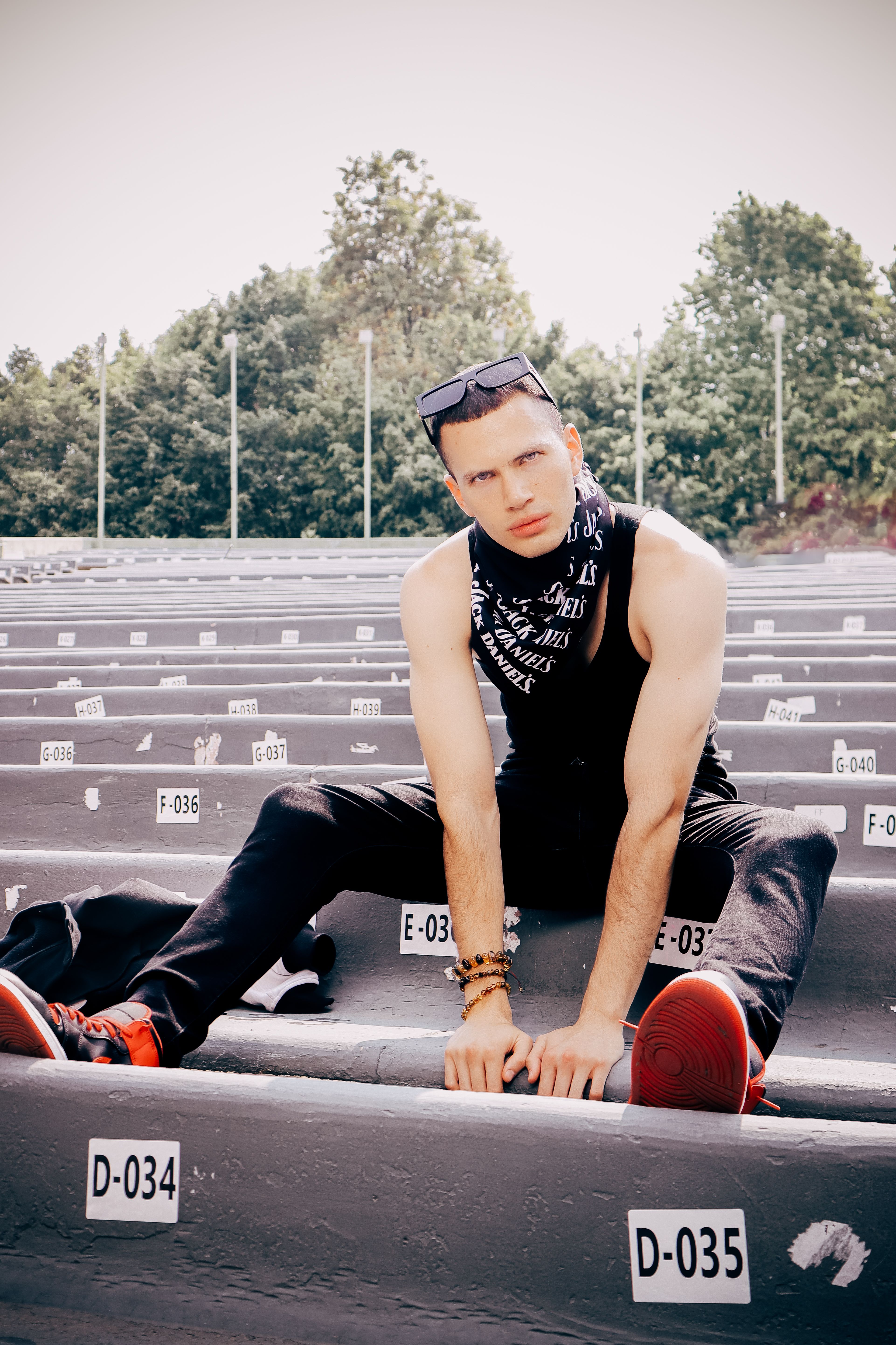 Stylish man in tank top and sunglasses poses outdoors in Mexico City.