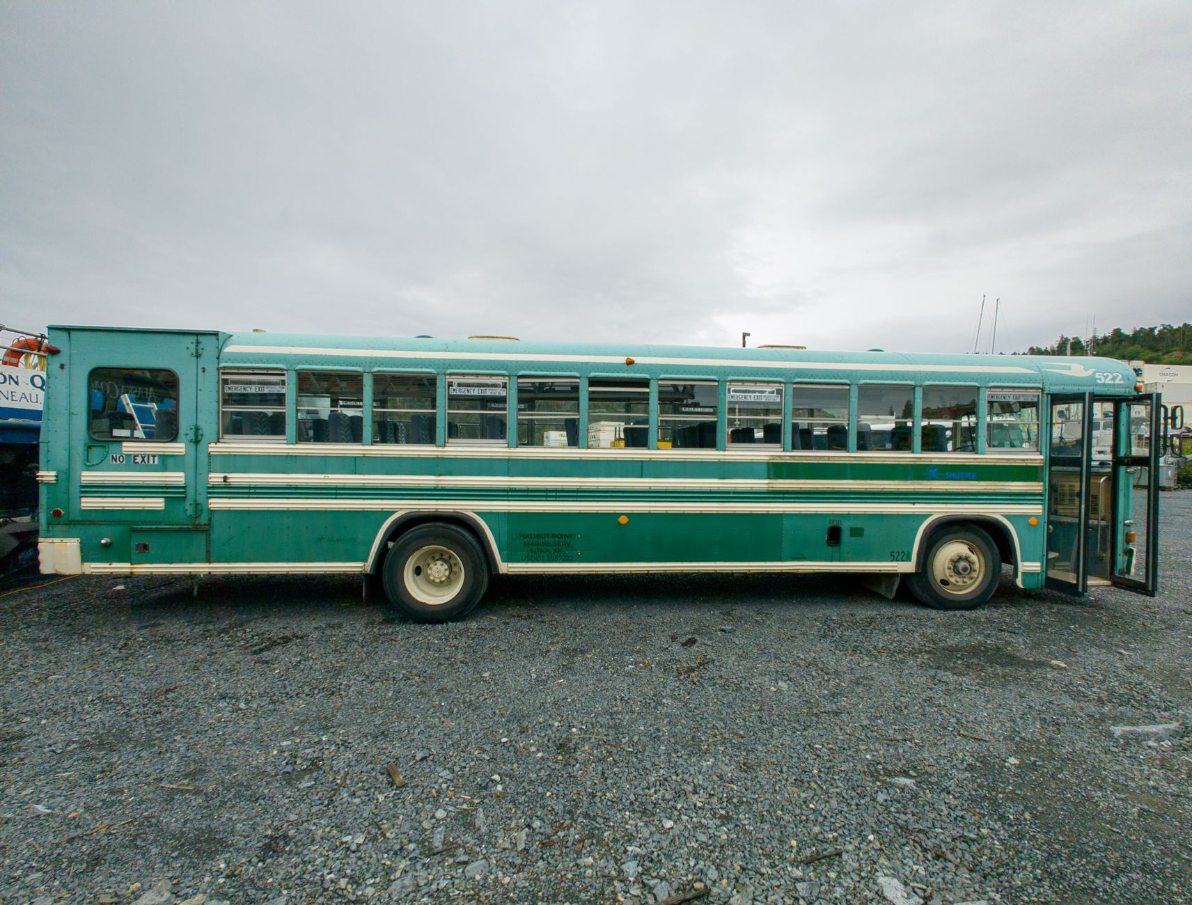 Vintage bus parked in an outdoor lot in Sitka, Alaska under overcast sky.