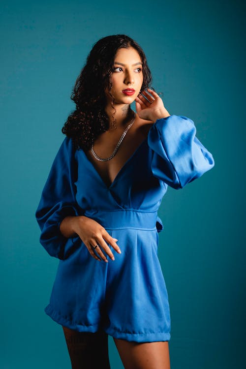 Young Woman Posing in a Blue Satin Long Sleeve Romper Dress