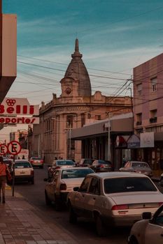 Street view of neoclassical architecture with traffic during evening in a South American city.