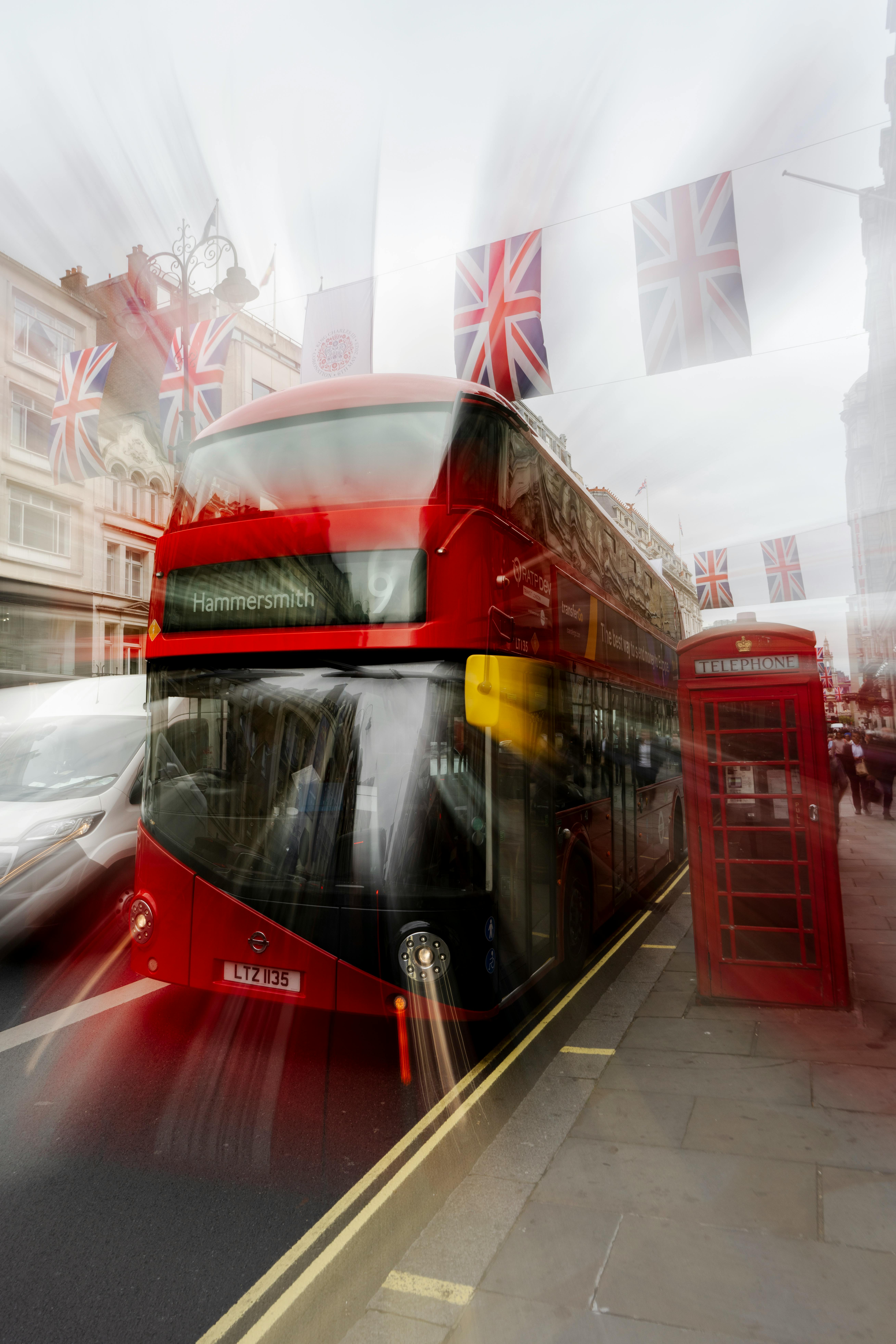 Blurred motion of a red double-decker bus and iconic phone booth in London, England.