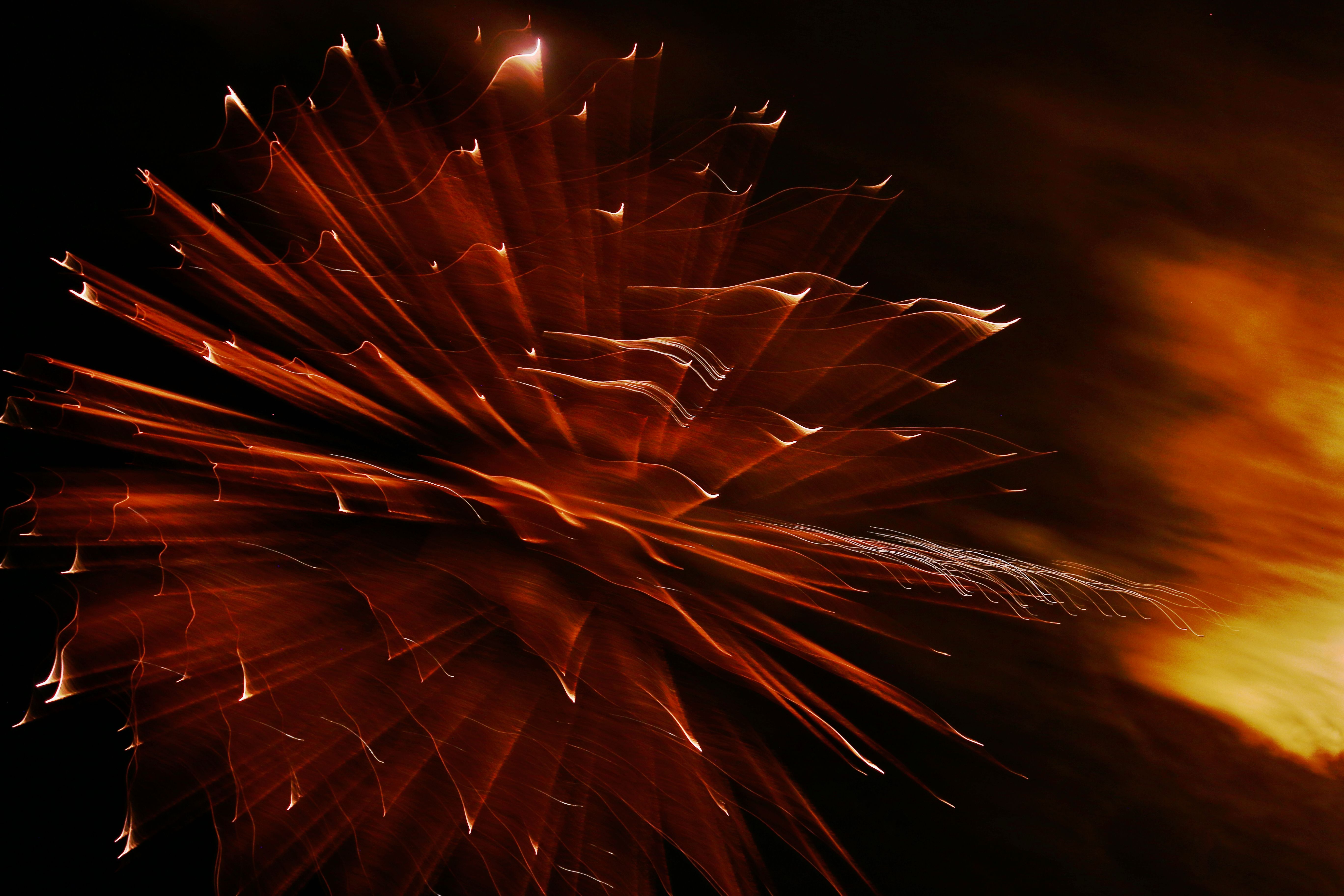 Dynamic long exposure of bright fireworks at night with abstract shapes and colors.