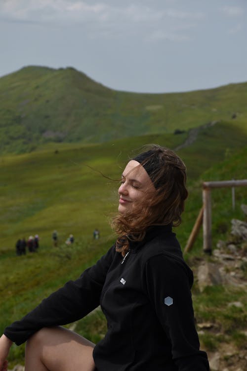 Smiling Woman Sitting with Eyes Closed in Countryside