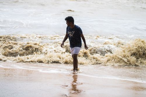 Free A man strolls along the beach, enjoying the summer waves at the seashore. Stock Photo
