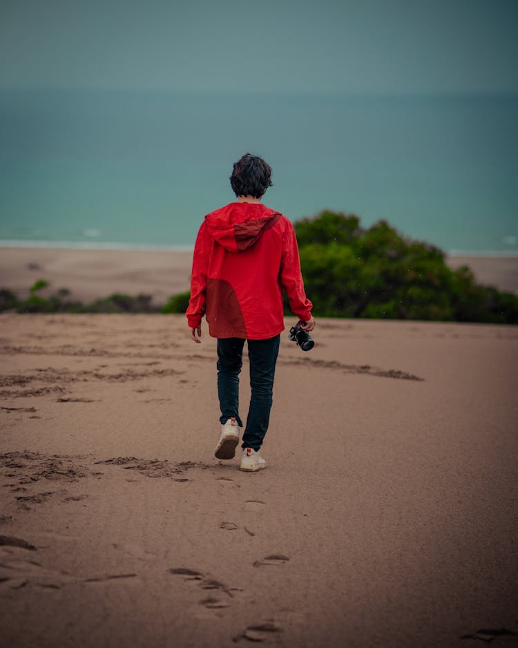 Man Walking With Camera On Beach