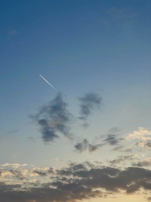 Plane Trail in Blue Sky with Clouds