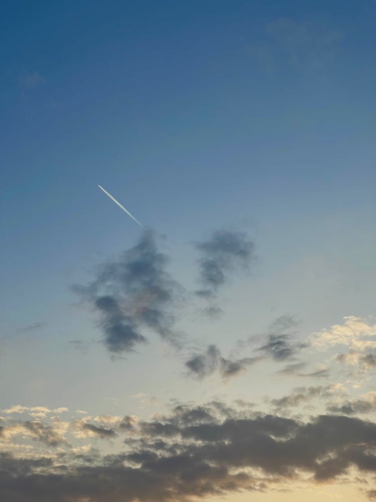 Plane Trail In Blue Sky With Clouds