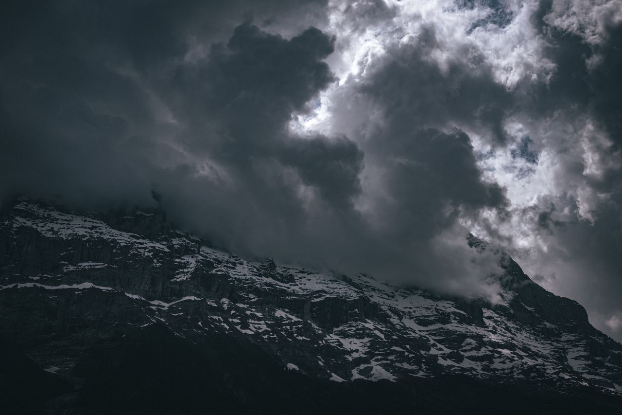 a dramatic view of snowcapped mountains shrouded in dark clouds creati