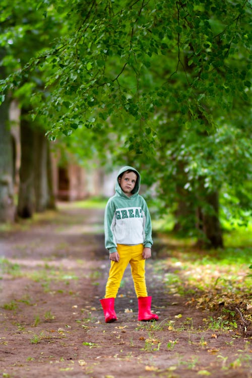 Boy in Rain Boots Standing on Road in Park