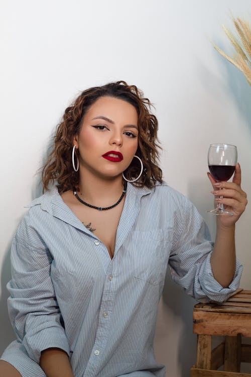 Young Woman with Red Lips Holding a Glass of Red Wine 