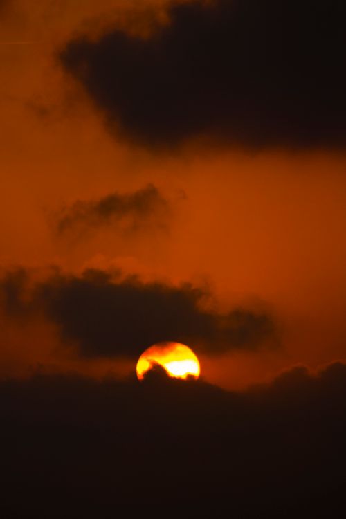 Free Captivating image of a dramatic sunset with golden clouds obscuring the sun, creating a vivid and warm scene. Stock Photo