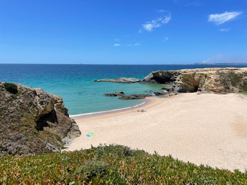 People Sunbathing on Sand Beach with Rocks