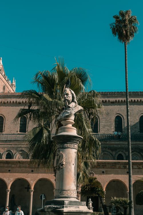 Free A statue set against an ancient building in Palermo's historic center under clear skies. Stock Photo