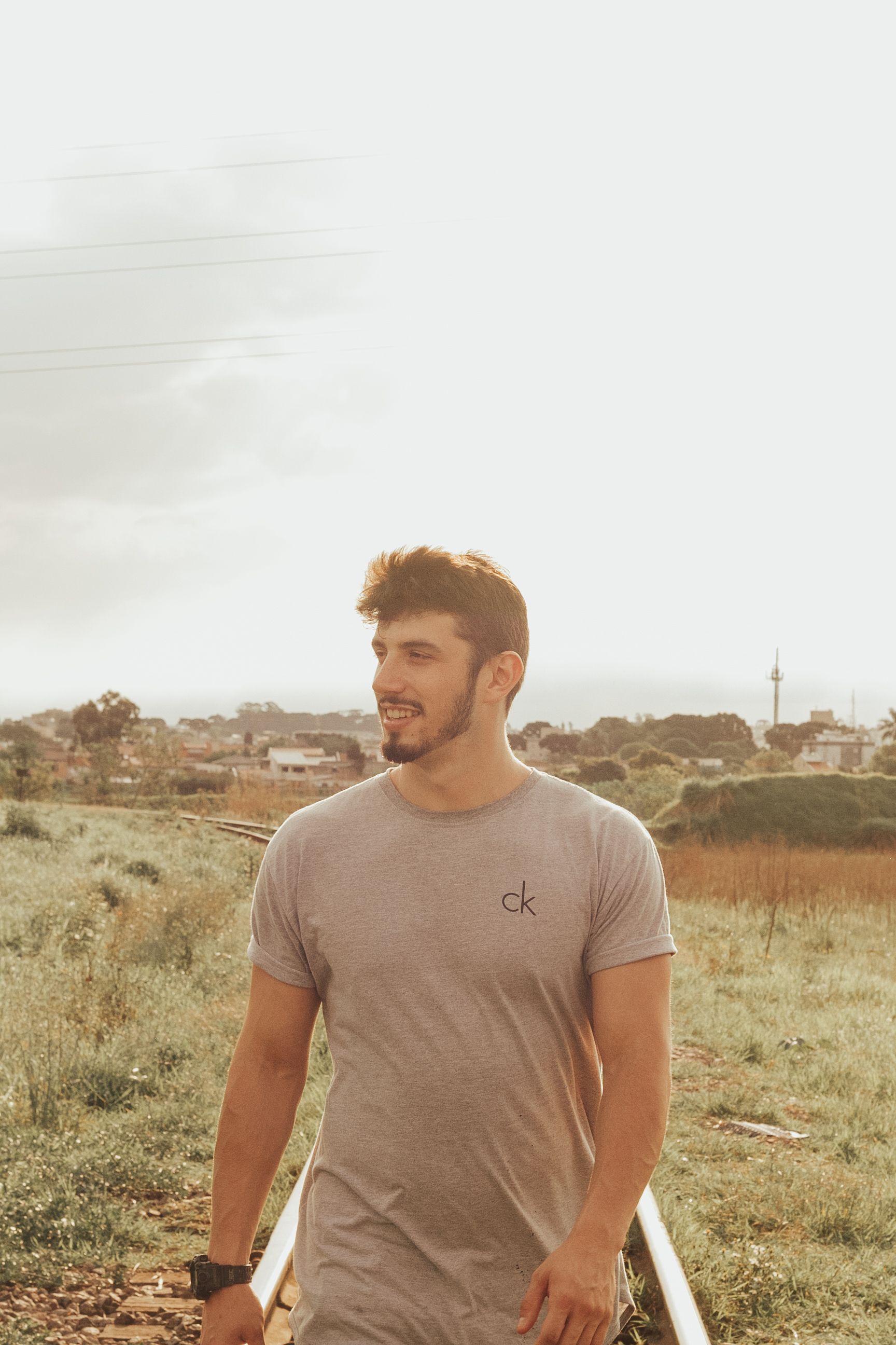 Portrait of a young man in casual attire walking outdoors on a sunny day in Pinhais, Brazil.