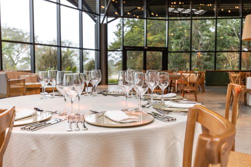 Free Luxuriously set restaurant table with glass walls and lush greenery view creating an inviting dining atmosphere. Stock Photo