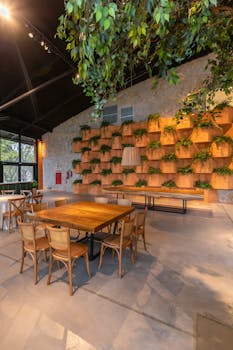 Contemporary restaurant interior featuring wooden tables, chairs, and lush greenery on walls.