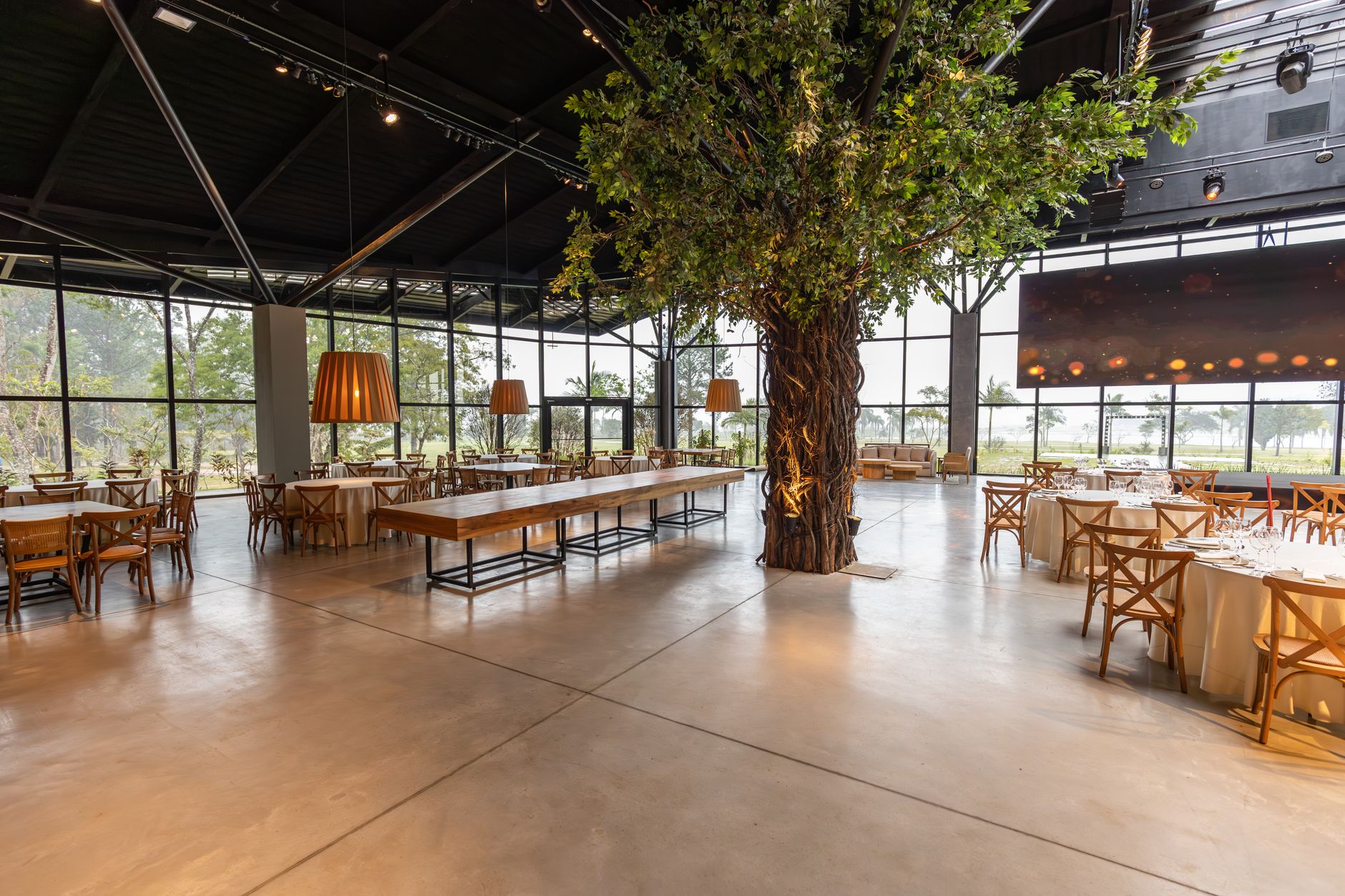 Spacious banquet hall featuring a unique indoor tree, elegant decor, and large windows offering a scenic view.