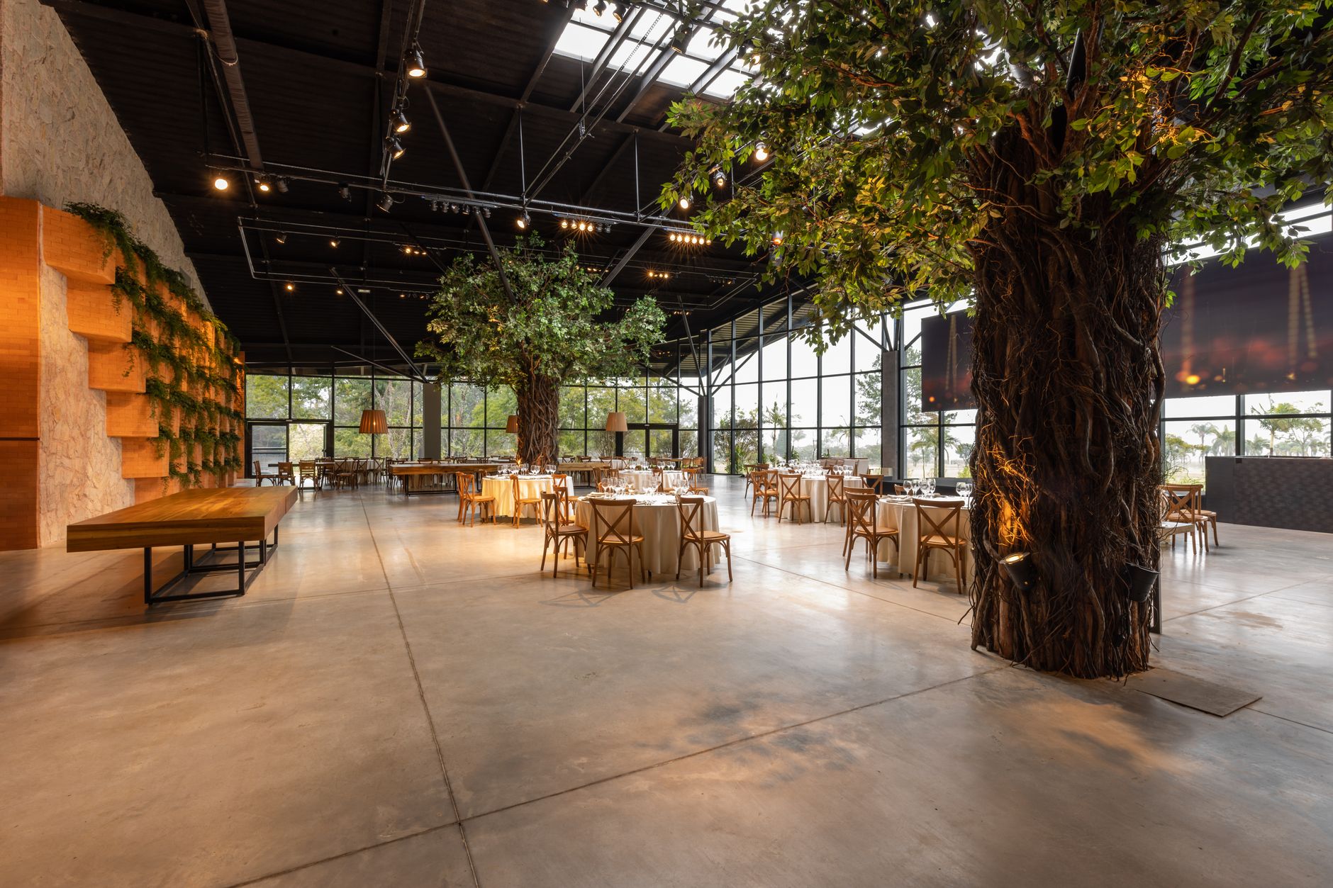 Spacious modern banquet hall featuring elegant tables and lush indoor trees.