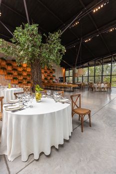 Stylish restaurant interior with round tables and indoor tree, perfect for events.