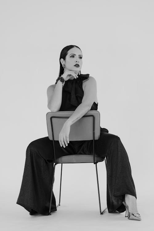 Black and White Studio Photo of a Woman Sitting on a Chair Backwards