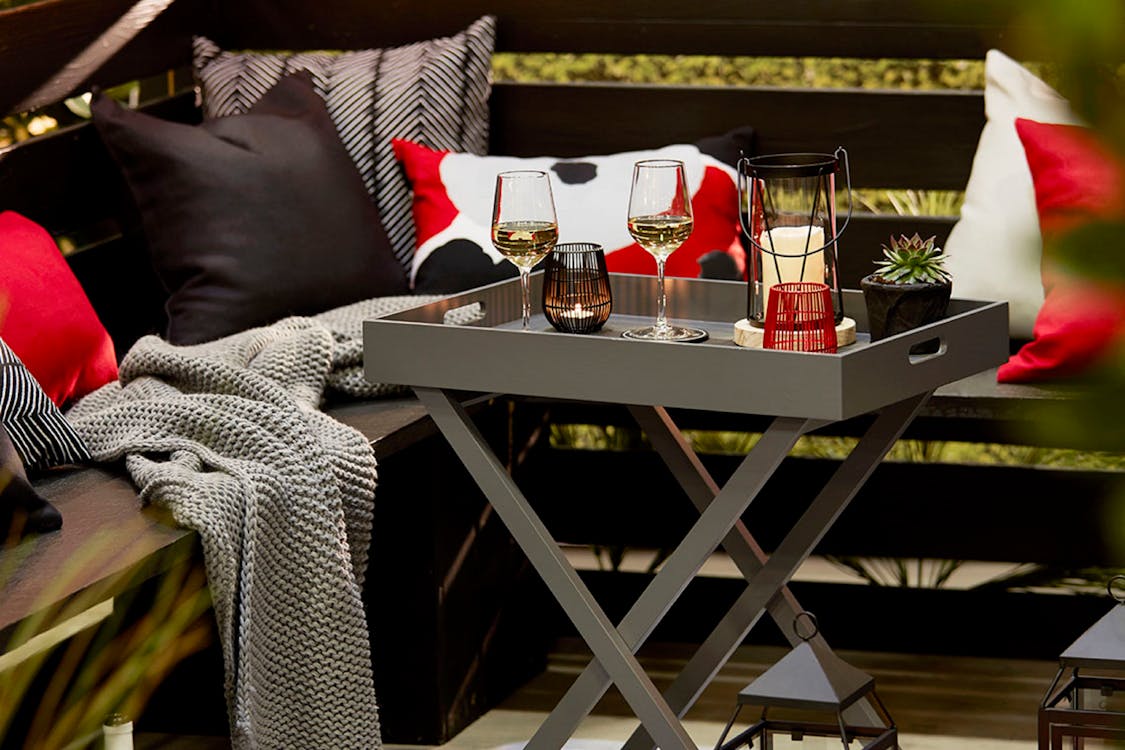 A set of outdoor furniture with a table and a couple of wine glasses on it