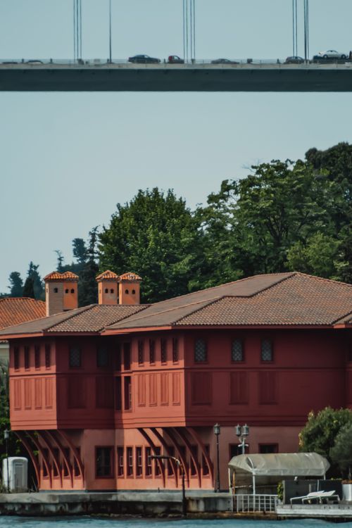 Free Vibrant red Ottoman-style building with lush greenery and bridge in İstanbul, Türkiye Stock Photo