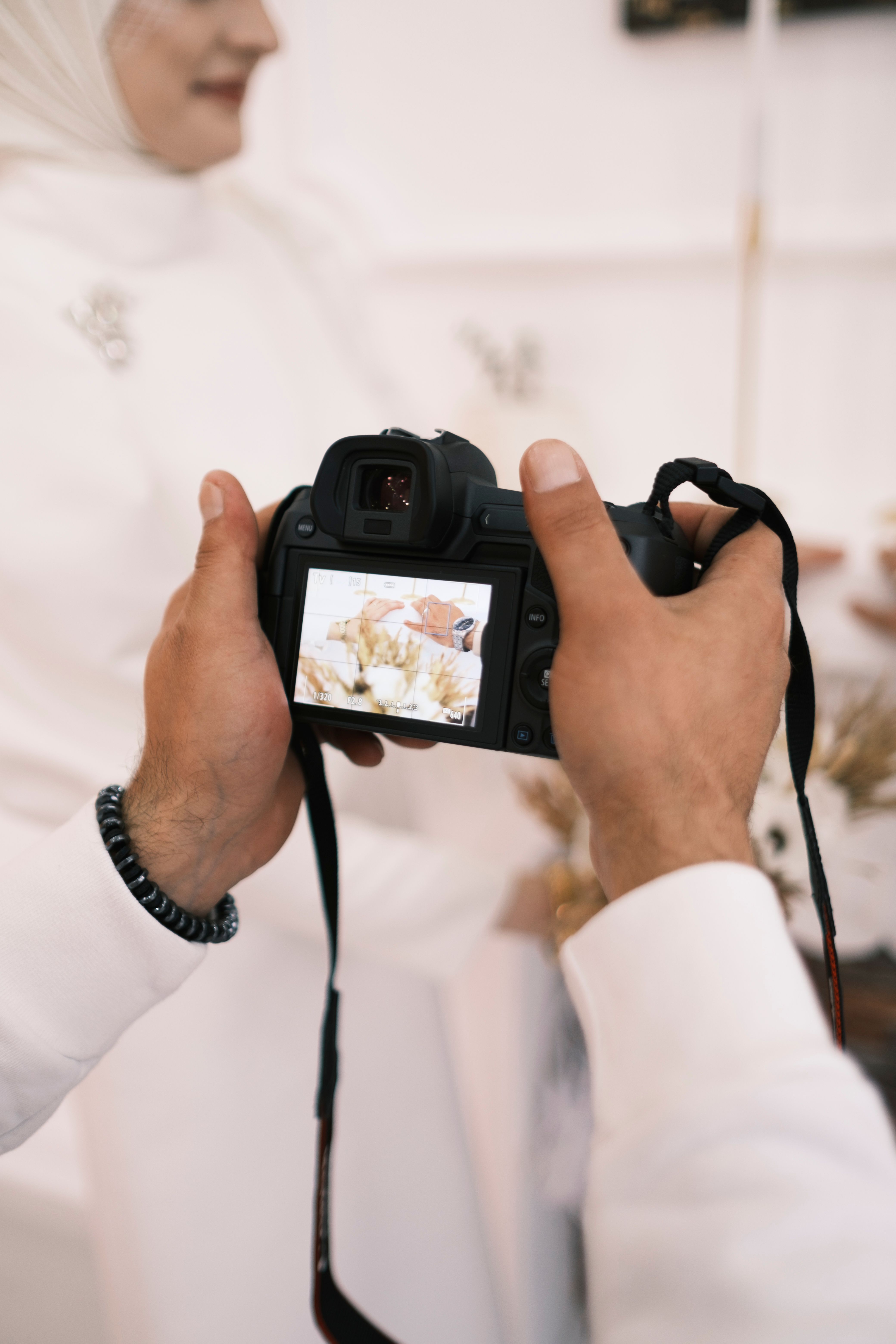 Close-up of a photographer's hands capturing wedding details with a digital camera.