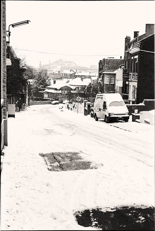 Free A quiet urban street blanketed in snow, showcasing a serene winter cityscape. Stock Photo
