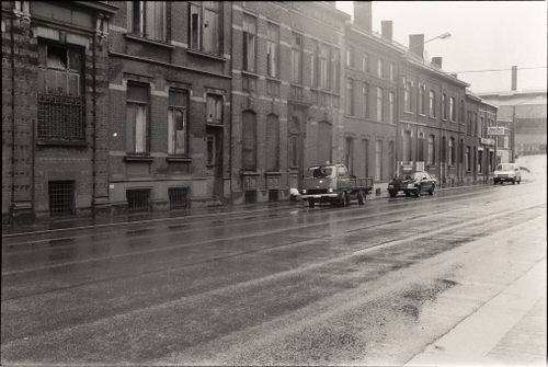 Free Vintage black and white photograph of a wet city street with old brick buildings. Stock Photo
