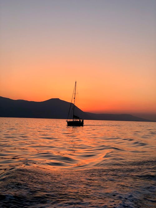 Silhouette of Sailing Sailboat on Coast at Sunset