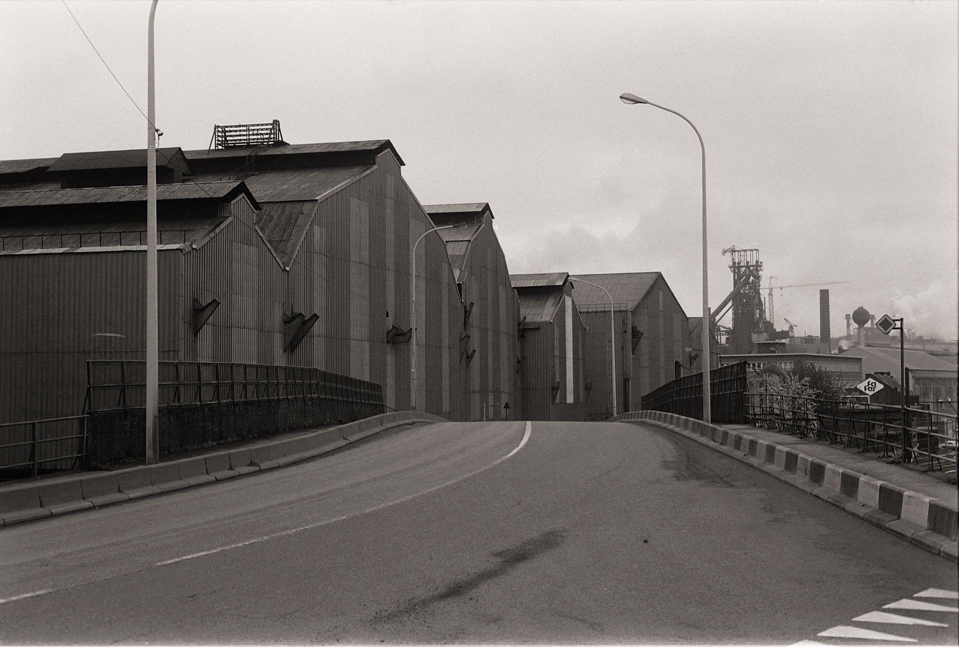 Black and white photo of warehouses in an industrial district with street view.
