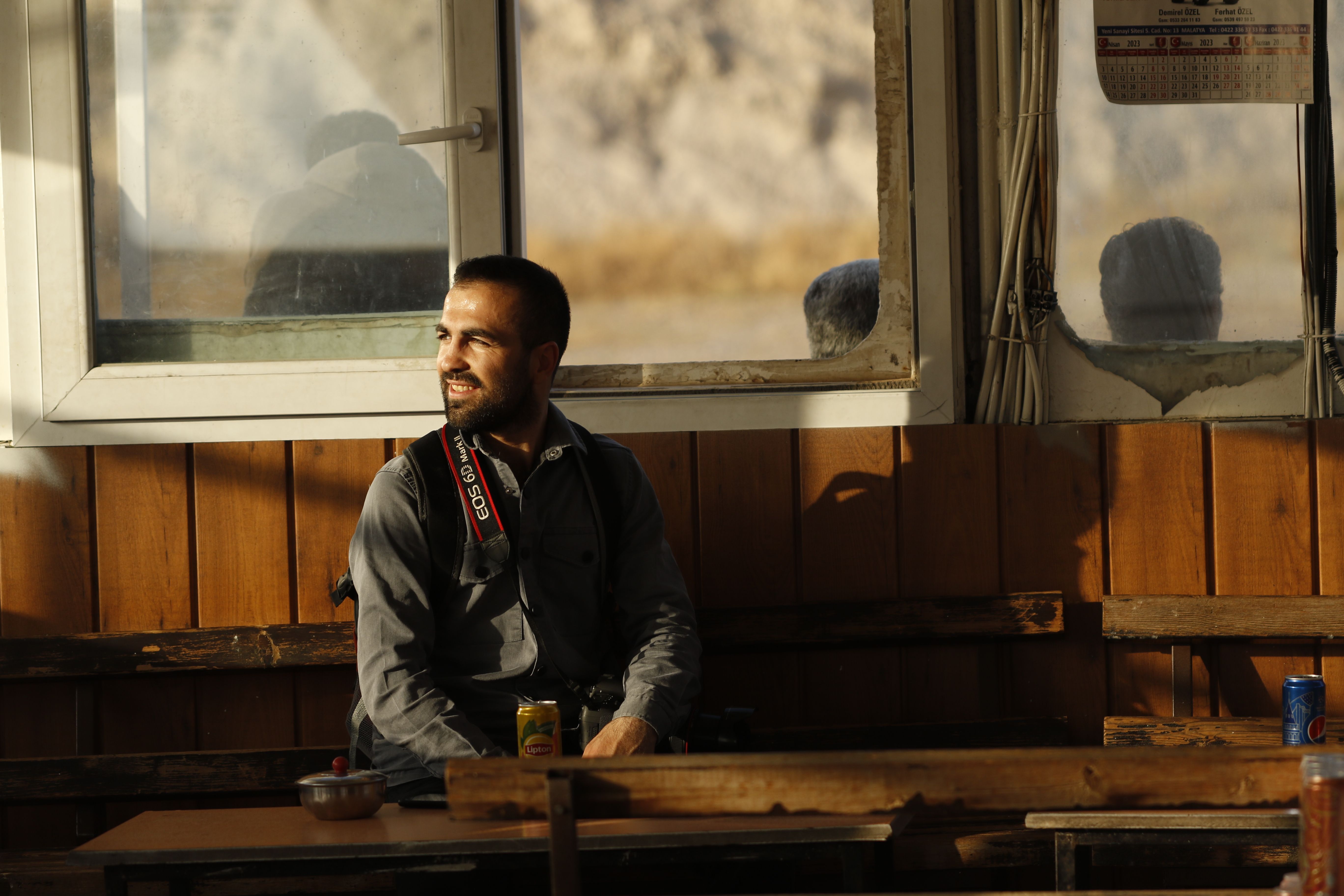 Man enjoying a relaxed moment by the window in a warm cafe setting, capturing natural sunlight.