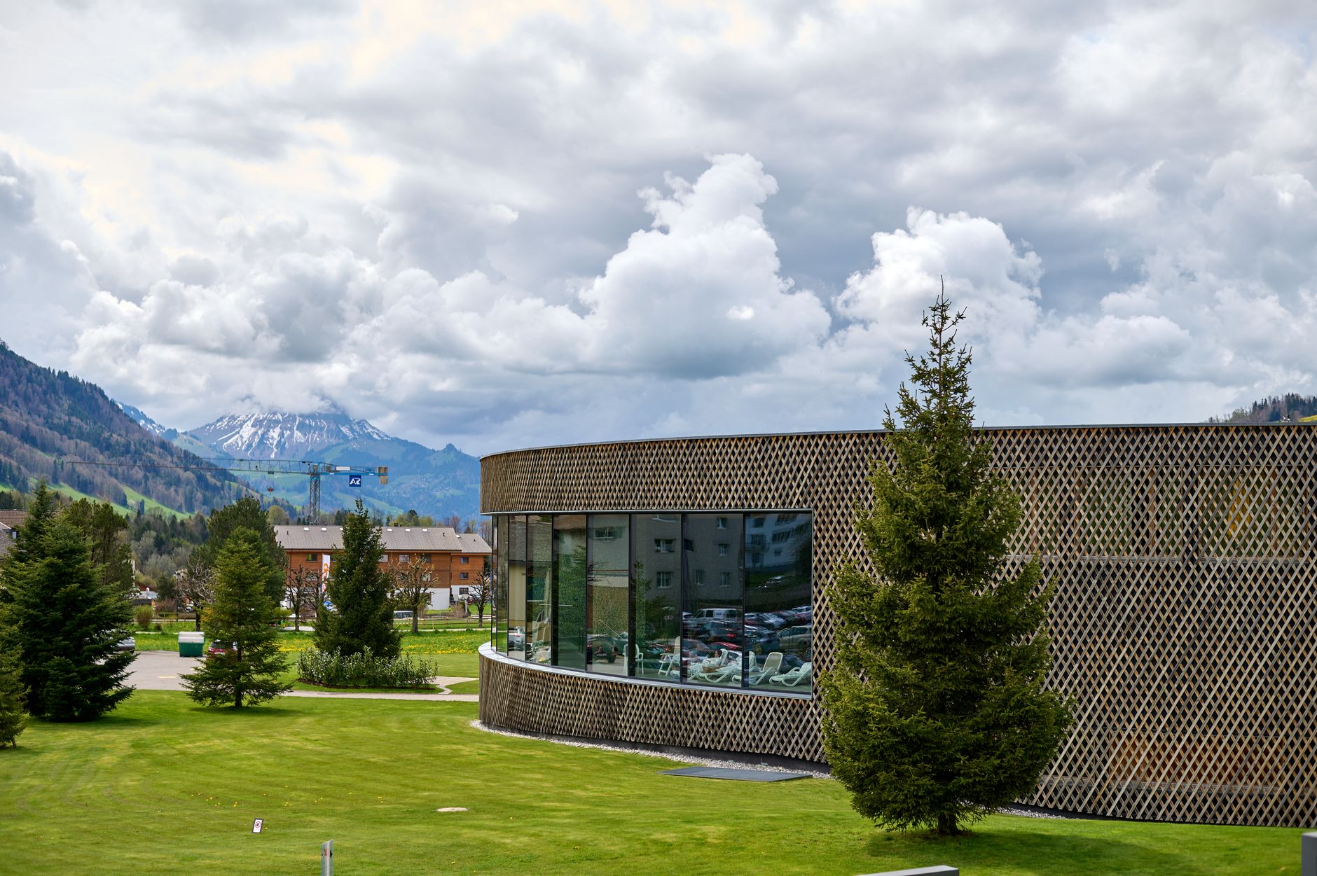 Contemporary building in Charmey with lush greenery and mountain backdrop.