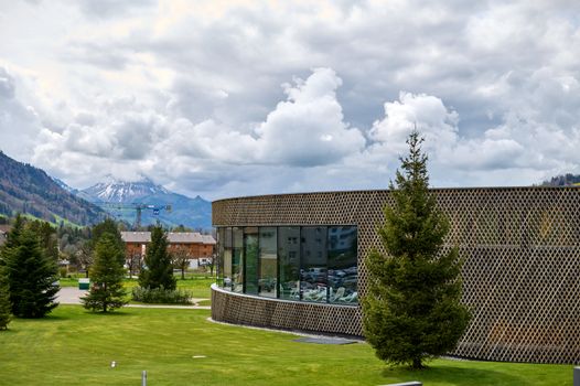 Contemporary building in Charmey with lush greenery and mountain backdrop.