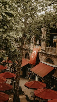 A vibrant Turkish street scene with red umbrellas and Turkish flag in view.