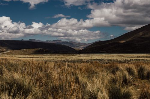 Free Breathtaking view of grassy plains and mountainous landscape under cloudy sky. Stock Photo