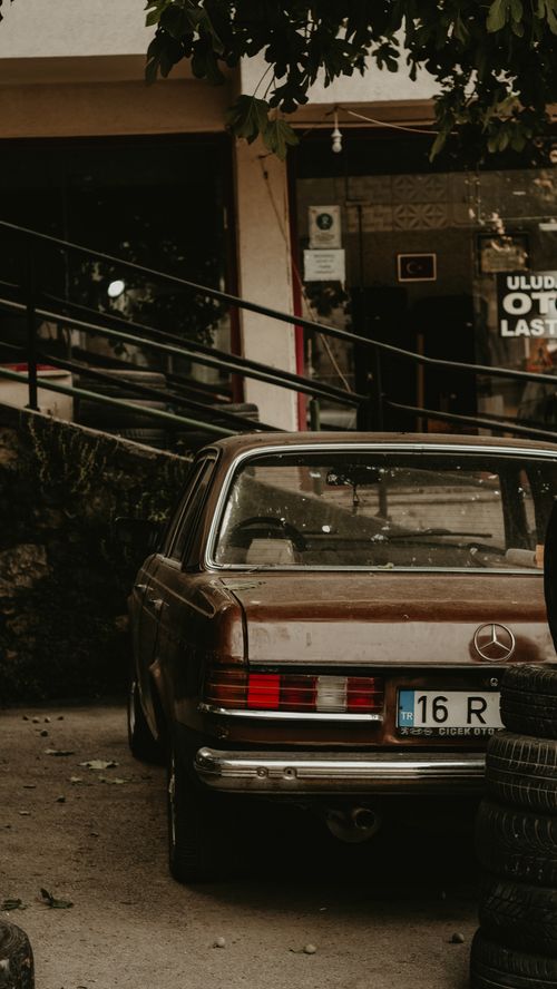 Free A retro Mercedes-Benz car parked outside a repair shop with classic rustic ambiance. Stock Photo