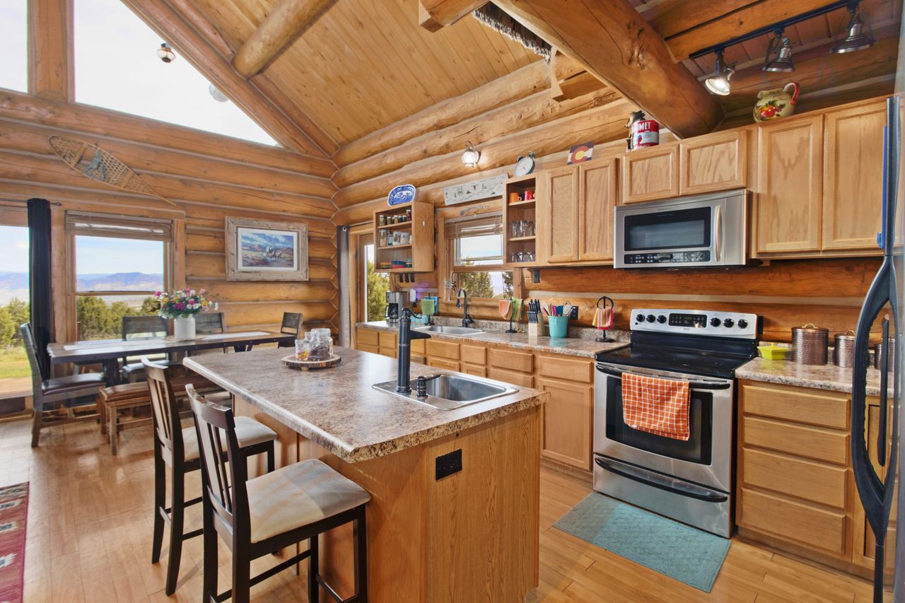 Log cabin kitchen with knotty pine cabinets, wood beam ceiling, and a large island