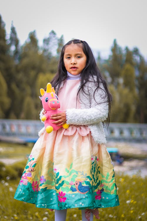 Girl in Colorful Dress Posing with Toy