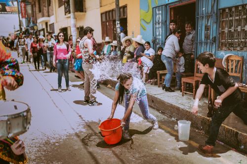 Free Colorful street festival in Cajamarca, Peru, featuring playful water splashing among children and locals. Stock Photo