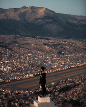 A person overlooking the cityscape of Cusco, Peru at sunset with the Andes mountains in the background.