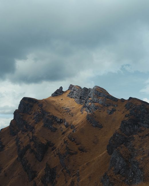 A breathtaking view of a rocky mountain peak under a cloudy sky in Cusco, Peru.