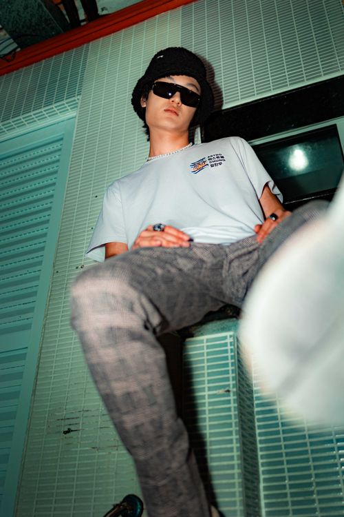 Free Teenage male in sunglasses, wearing a t-shirt and checkered pants, in an urban setting. Cool and stylish. Stock Photo