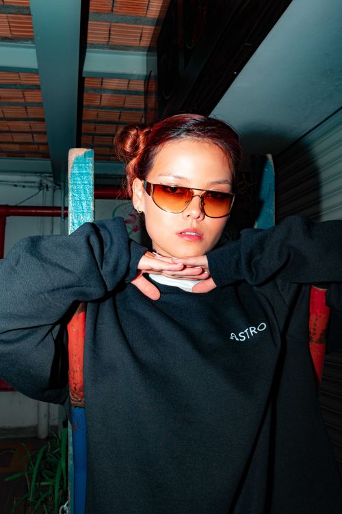 Free A confident woman poses in a black sweatshirt and sunglasses, showcasing modern street style. Stock Photo