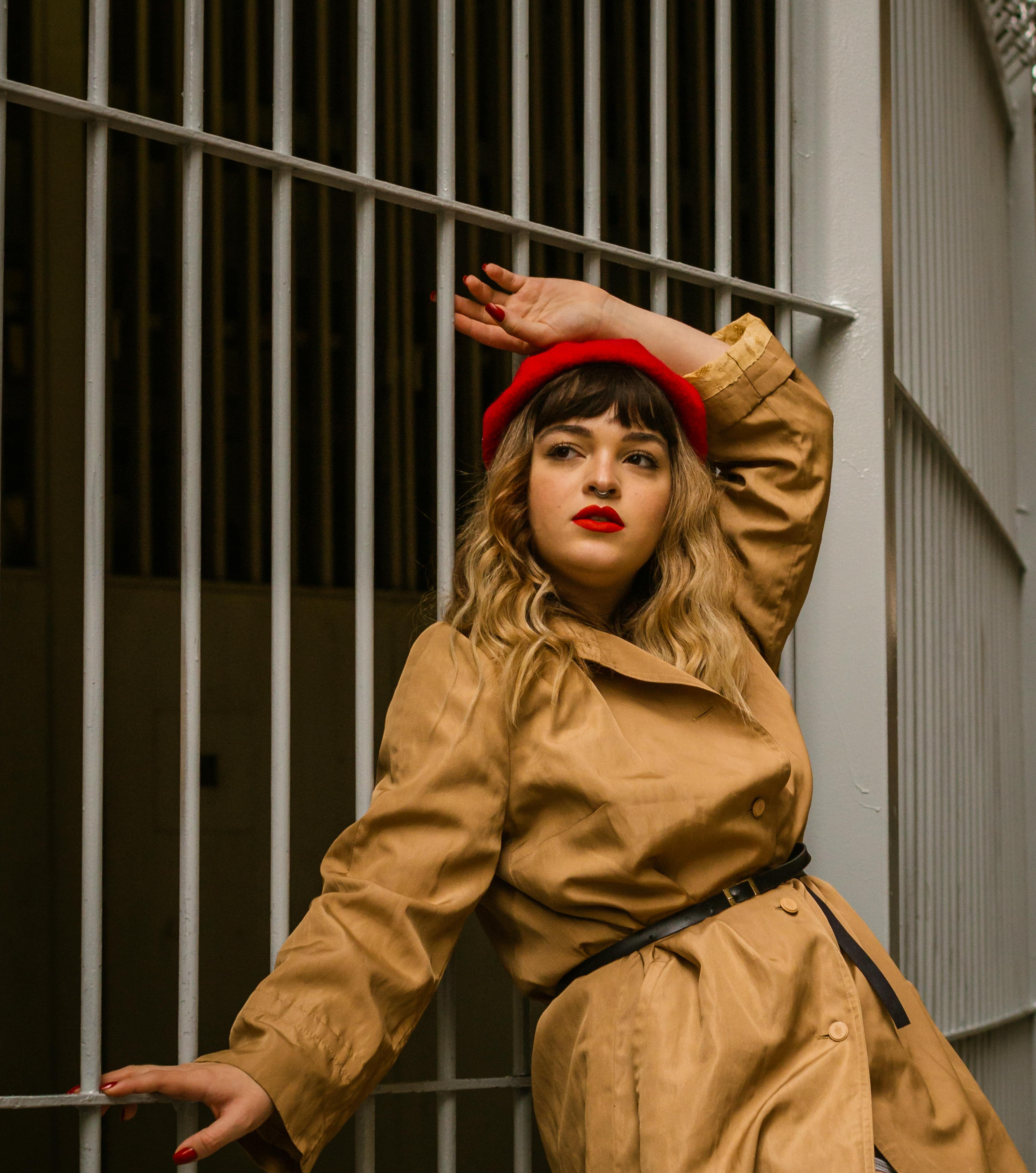 Free A fashionable woman poses elegantly in a trench coat and red beret. Stock Photo