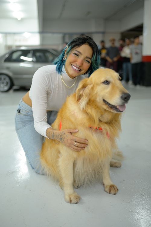 Free Smiling woman with dyed hair hugging golden retriever indoors, showcasing bond with pets. Stock Photo