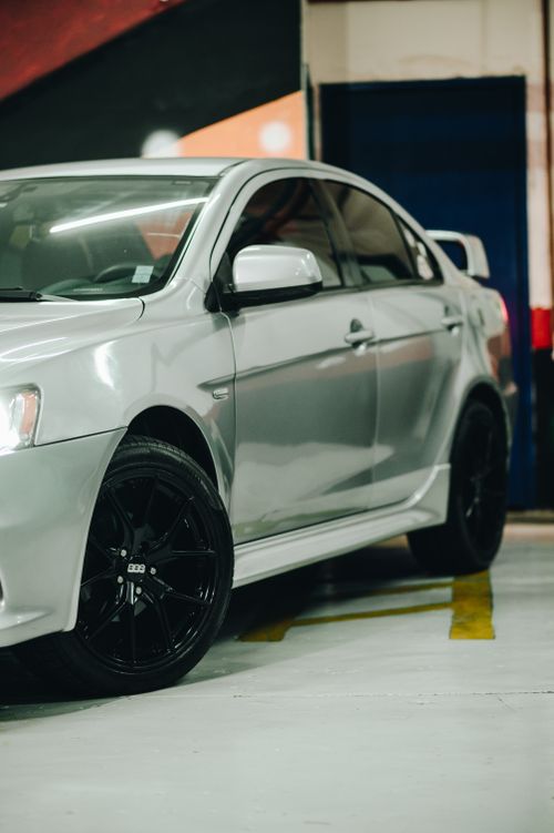 Free Close-up of a silver Mitsubishi Lancer parked in an indoor garage setting. Stock Photo