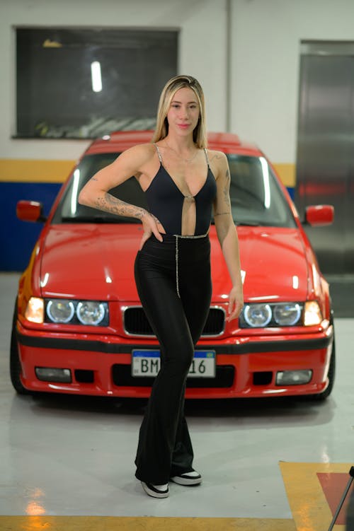 Blonde Woman Posing by Red Car with Hand on Hip