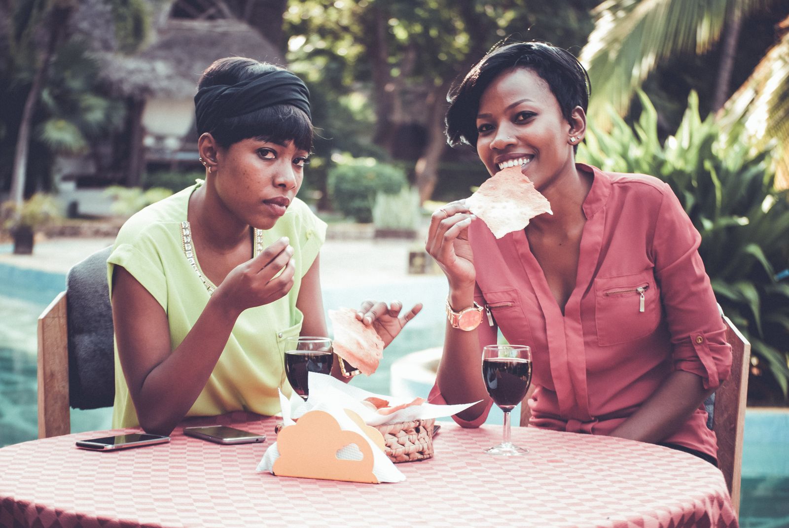 Two Black women sharing food and wine