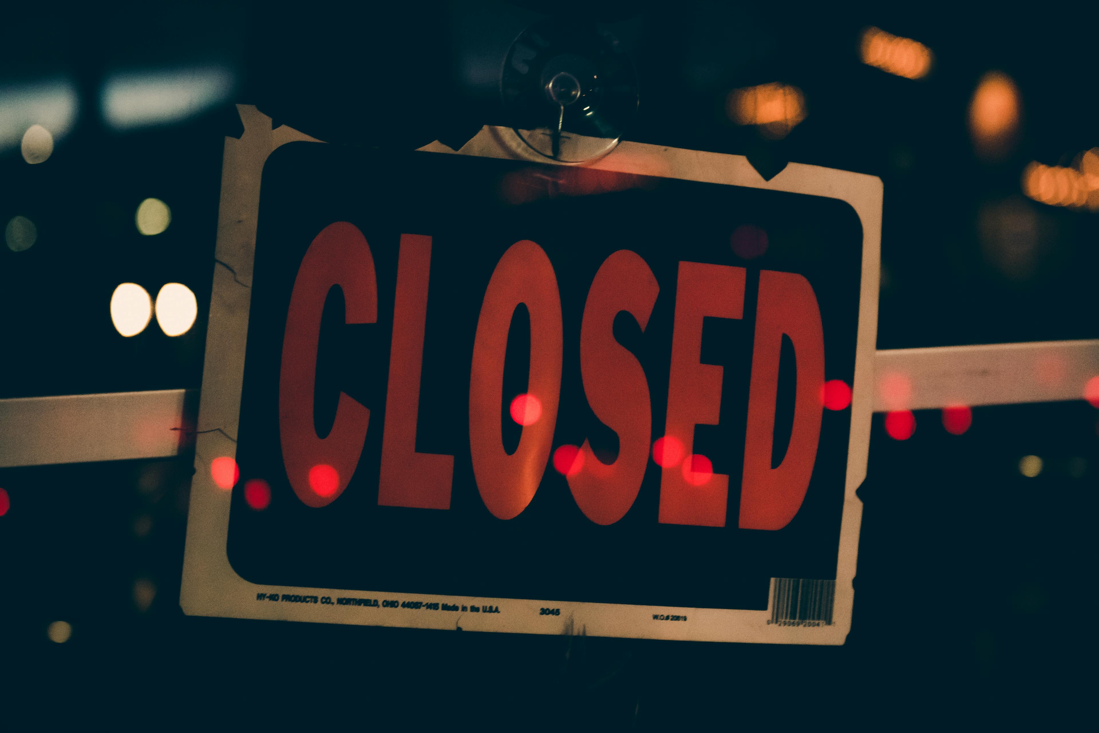 Moody image of a closed sign with bokeh lights, conveying nighttime closure.